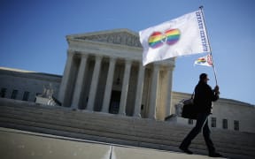 An activist from Equality Beyond Gender holds a marriage pride flag outside the U.S. Supreme Court January 2015.