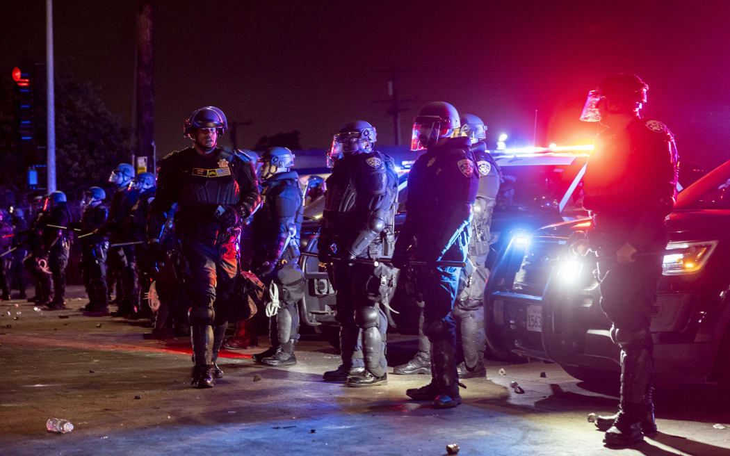 Law enforcement officers stand guard as they face off with demonstrators during a protest following federal immigration operations, in the Compton neighborhood of Los Angeles, California early on June 8, 2025. US President Donald Trump deployed 2,000 troops on June 7 to handle escalating protests against immigration enforcement raids in the Los Angeles area, a move the state's governor termed "purposefully inflammatory." Federal agents clashed with angry crowds in a Los Angeles suburb as protests stretched into a second night Saturday, shooting flash-bang grenades and shutting part of a freeway amid raids on undocumented migrants, reports said. (Photo by ETIENNE LAURENT / AFP)