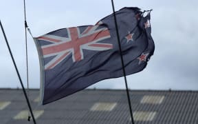 Tattered New Zealand flag flying high on a yacht in Wellington.