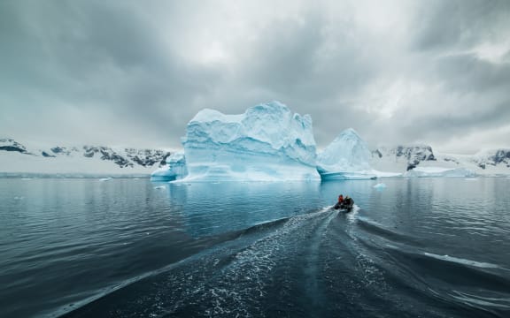 A small inflatable boat heads out to the iceberg Lincoln