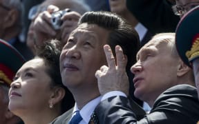 Russian President Vladimir Putin (R) speaks with Chinese President Xi Jinping (C) during the Victory Day parade in Moscow.