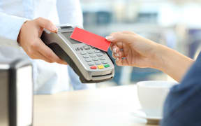 Close up of a customer hand paying with a contactless credit card reader in a bar
