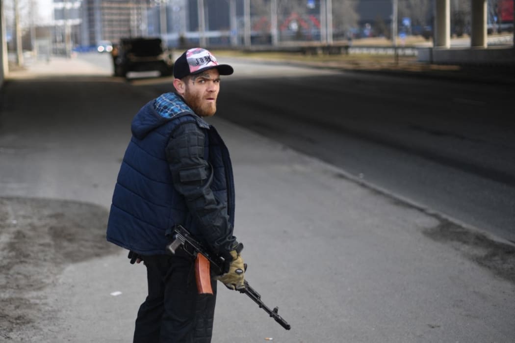 A volunteer, holding a rifle, protects a main road leading into Kyiv on February 25, 2022. - Ukrainian forces fought off Russian invaders in the streets of the capital Kyiv on February 25, 2022,