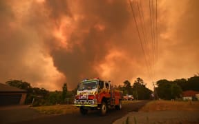 Firetrucks are seen stationed on a road as a bushfire burns in Bargo, southwest of Sydney on December 21, 2019.