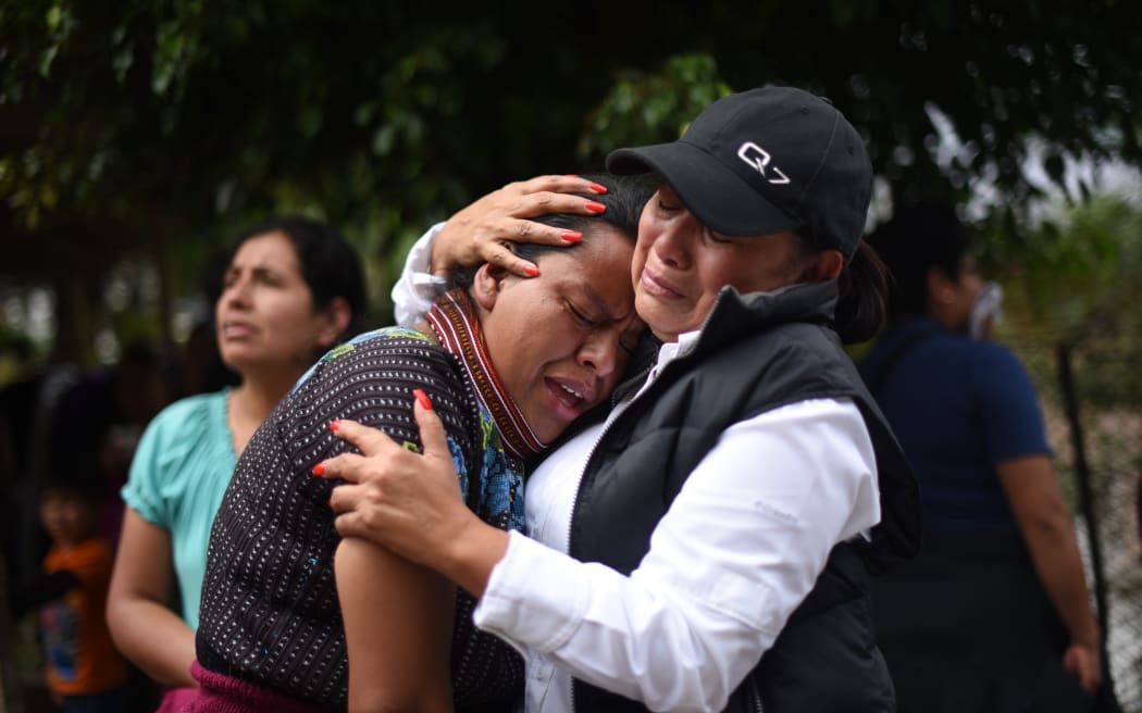 Women cry outside a provisional morgue in the village of El Cambray.