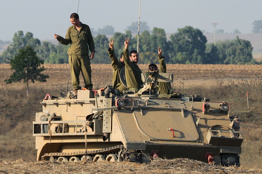 Israeli soldiers flash the sign for victory at an army deployment area near Israel's border with the Gaza Strip.