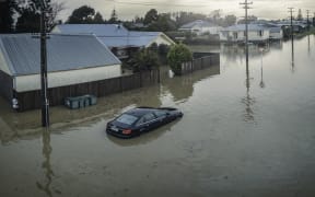 A partly-submerged car outside flooded houses on Disraeli St, Westport.