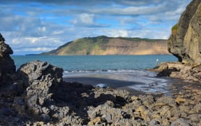 Cliffs and rock formations along black sand Whatipu Beach in Huia, West Auckland in New Zealand