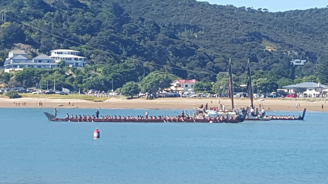 Waka crews salute tohunga waka Hek Busby (on board the waka hourua  at Waitangi this morning.