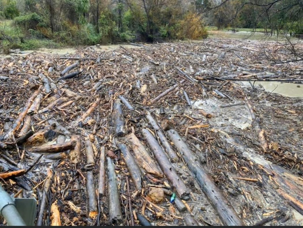 Contractors work to clear logs from as river along Paroa Rd north of Tolaga Bay.