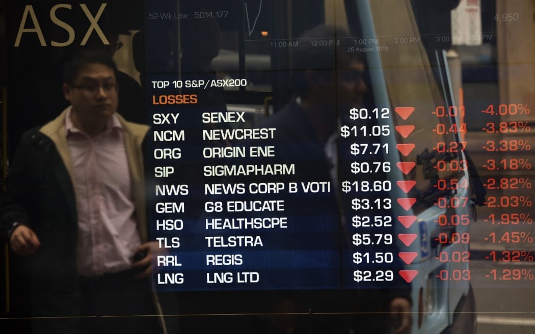 A man is reflected in a window as data on an electronic share board is seen at the Australian Stock Exchange in Sydney on August 25, 2015.