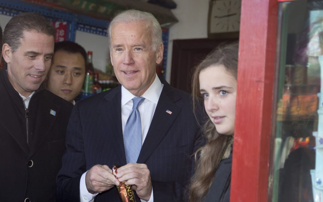 US Vice President Joe Biden (C) buys an ice-cream at a shop as he tours a Hutong alley with his granddaughter Finnegan Biden (R) and son Hunter Biden (L) in Beijing on December 5, 2013.