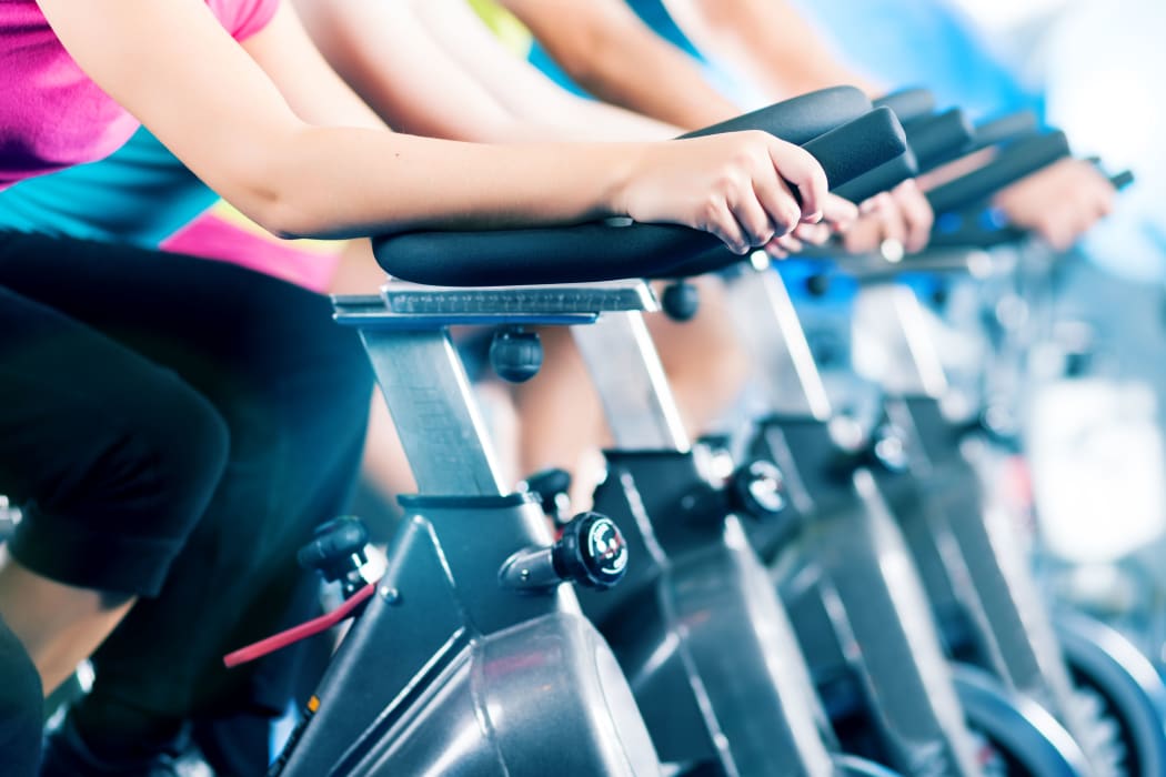 Group of four people spinning in the gym, as they take part in a HIIT class.