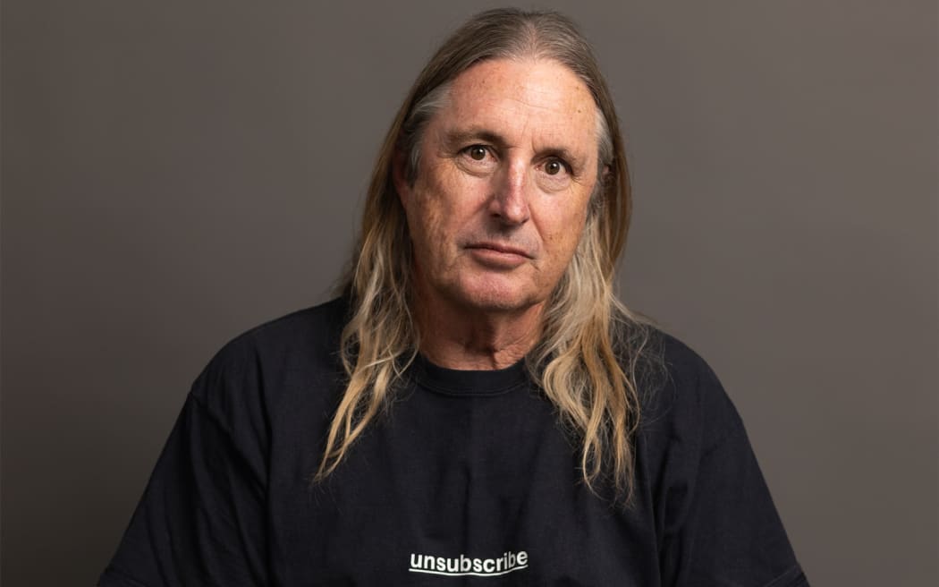 The writer Tim Winton has long hair and a black t-shirt with the word 'unsubscribe'