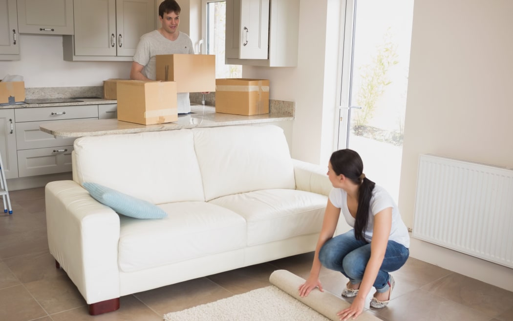 16053421 - two young people moving into their house and furnishing the living room
