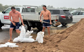 Two men filling sandbags in the rain in Townsville.