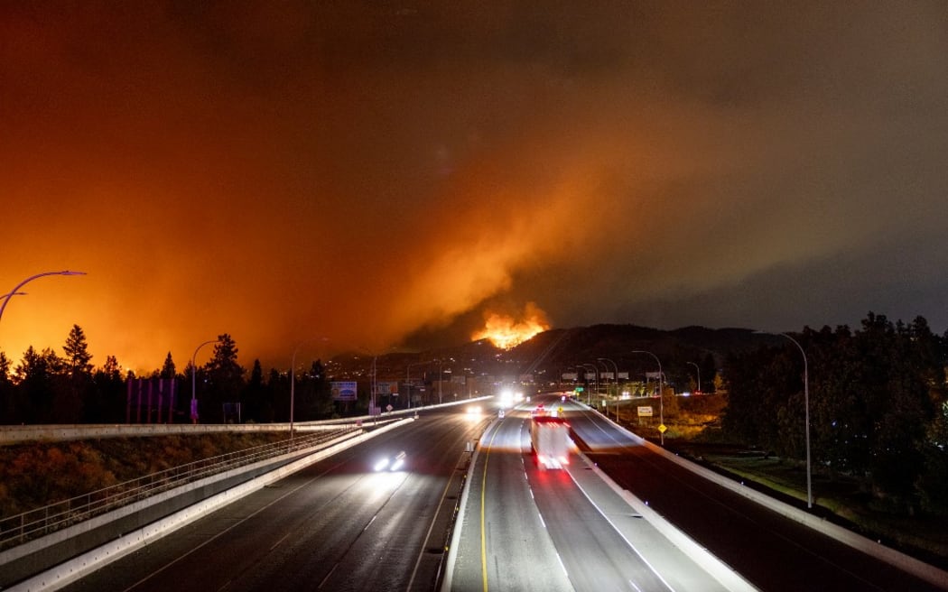 The McDougall Creek wildfire burns in the hills West Kelowna, British Columbia, Canada, on August 17, 2023, as seen from Kelowna. Evacuation orders were put in place for areas near Kelowna, as the fire threatened the city of around 150,000. Canada is experiencing a record-setting wildfire season, with official estimates of over 13.7 million hectares (33.9 million acres) already scorched. Four people have died so far. (Photo by Darren HULL / AFP)