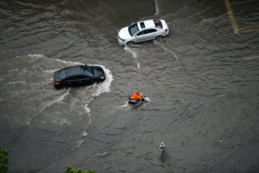 People ride in the waterlogging caused by rainstorm in Zhengzhou city, central China's Henan province.