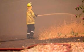 This frame grab from video footage taken and provided by Australian Broadcast Corporation (ABC) on December 21, 2023 via AFPTV shows firefighters in the suburb of Parkerville, east of Perth, attempting to put out a bushfire.