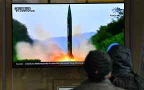People watch a television news broadcast showing a file image of a North Korean missile test, at a railway station in Seoul on March 21, 2020. - North Korea on March 21 fired two projectiles presumed to be short-range ballistic missiles into the sea off its east coast, Seoul's military said.