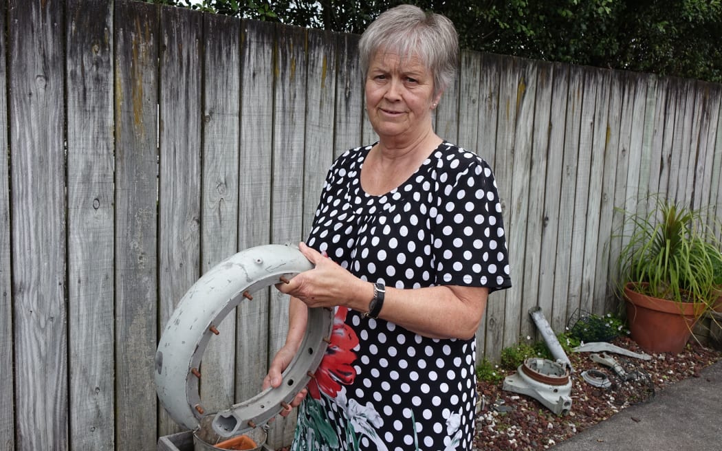 Helene Green stands near a fence holding metal parts