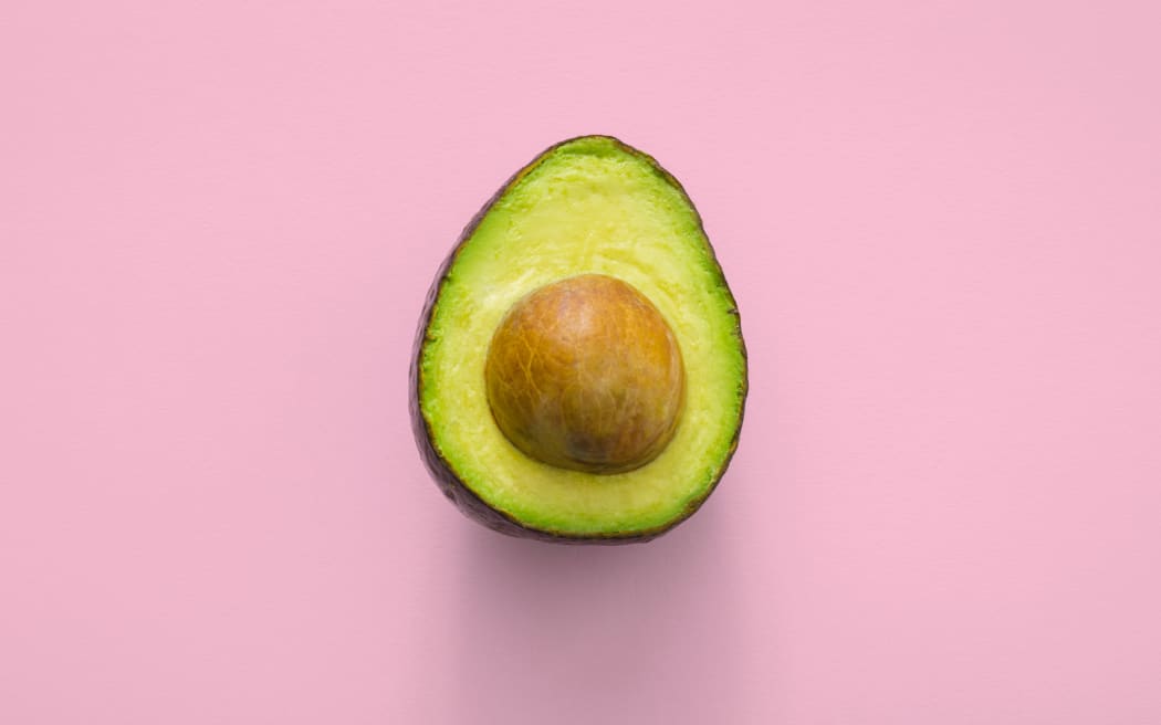 an avocado with a pink background