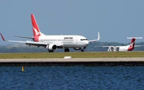 A Qantas Boeing 737, left,lands as a Qantas Q-400, right, prepares to take off at Sydney International Airport in November 2011.