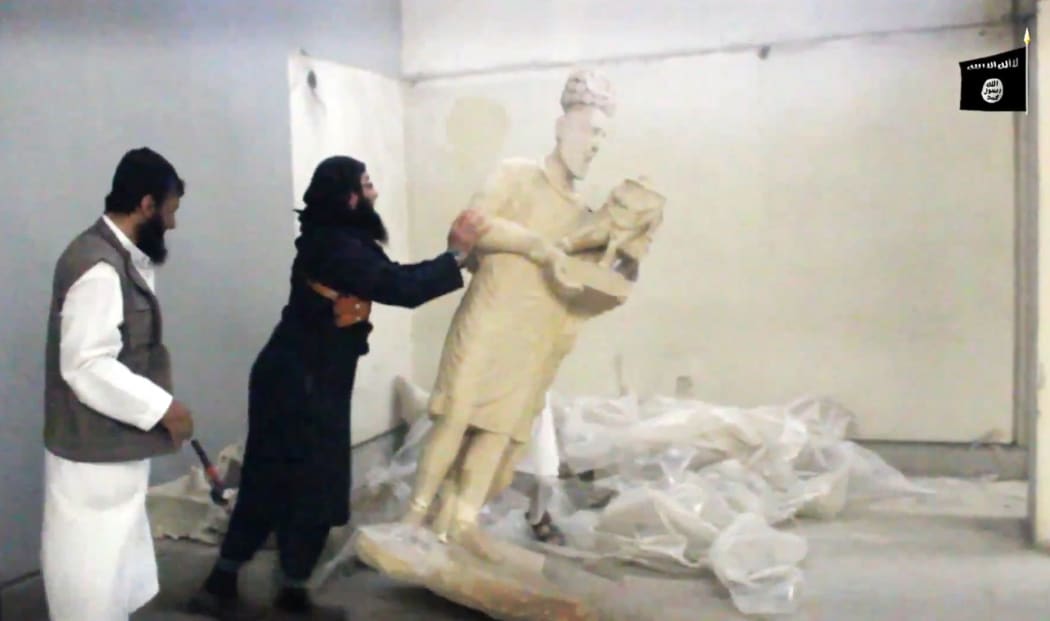 An image grab taken off a video by Islamic State allegedly shows a militant pushing a statue inside the Mosul museum.