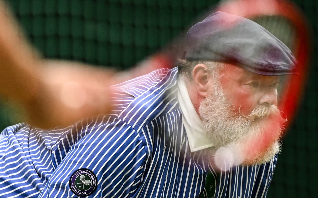 A line umpire is pictured through the racket of USA's Tommy Paul during his men's singles quarter-finals tennis match against Spain's Carlos Alcaraz at Wimbledon in 2024.  (Photo by Ben Stansall / AFP) / RESTRICTED TO EDITORIAL USE