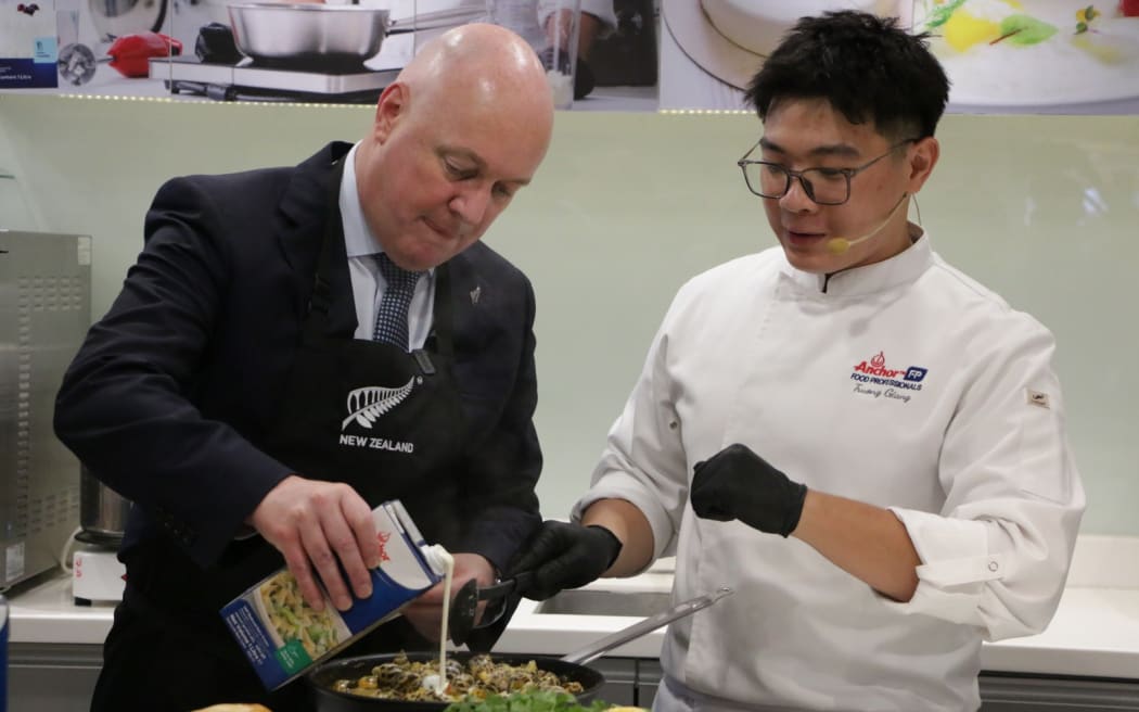 Christopher Luxon participates in a cooking demonstration at Fonterra's headquarters in Ho Chi Minh City. He is adding cream from New Zealand to some Vietnamese molluscs.