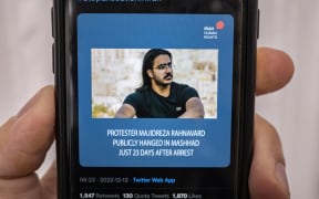A mobile phone displays a Tweet about the execution announced by Iranian authorities of Majidreza Rahnavard, the second capital punishment linked to nearly three months of protests, 12 December 2022.