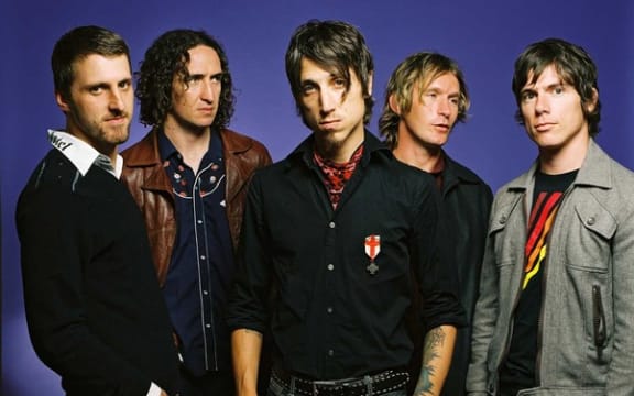 Five men stand in a line looking tough.