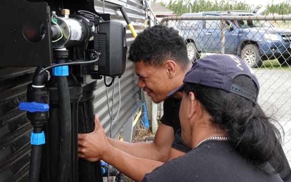 Tengo Christie installs a water filter while fellow tauira (trainee) Gabe Wharekawa looks on.