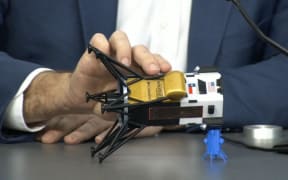 This frame grab from Nasa, shows Intuitive Machines CEO Steve Altemus holding a model of Odysseus to show its position on the side during a press conference at Johnson Space Center in Houston, Texas on February 23, 2024. The first American spaceship on the Moon since Apollo probably face-planted into the dirt after catching on a rock during its dramatic landing, the company that built it said Friday. (Photo by Handout / NASA TV / AFP)