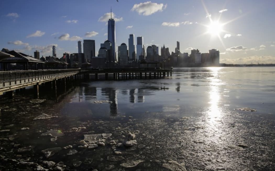 Ice floats along the Hudson River, with  the skyline of New York City and One world Trade Center.