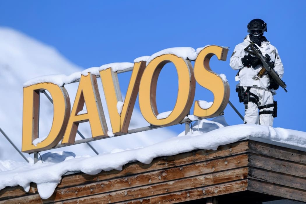 A Swiss police sniper stands guard on the roof next to the Congress centre during the first day of the WEF.
