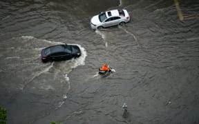 People ride in the waterlogging caused by rainstorm in Zhengzhou city, central China's Henan province.
