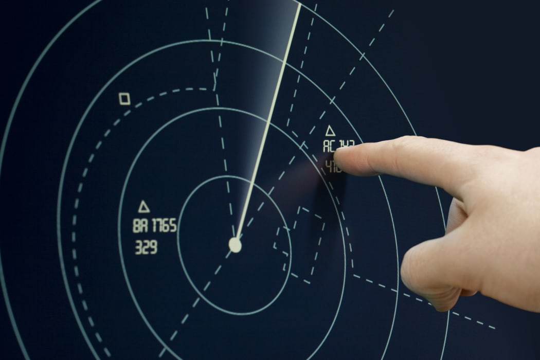 Air traffic controller points to a plane on radar.