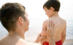 Father putting sunscreen on boy.
