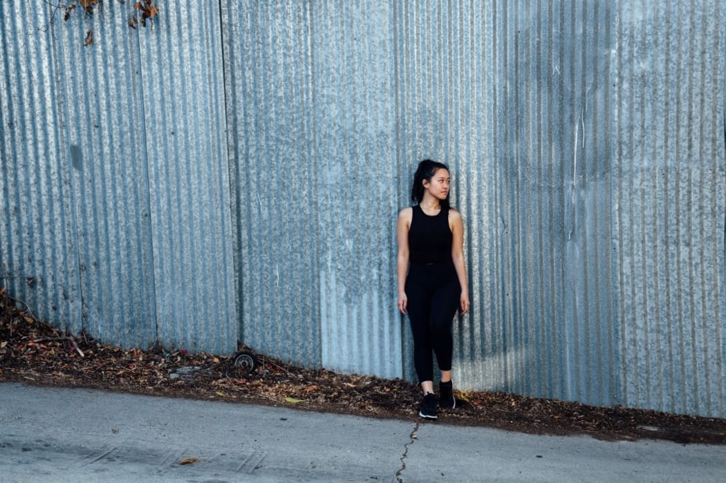 Portrait of young woman standing in front of corrugated fencing (Photo by Ashley Corbin-Teich / Image Source / Image Source via AFP)