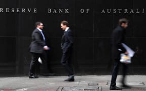 Office employees walk in front of the Reserve Bank of Australia in Sydney on September 4, 2018. - Weak inflation, sluggish wage growth and high levels of household debt saw Australia's central bank keep interest rates on hold at a record low on September 4. (Photo by Saeed KHAN / AFP)