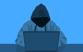 Hooded figure in front of laptop