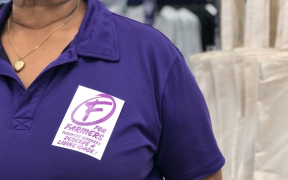 A Farmers worker wearing a sticker protesting the company's wages.
