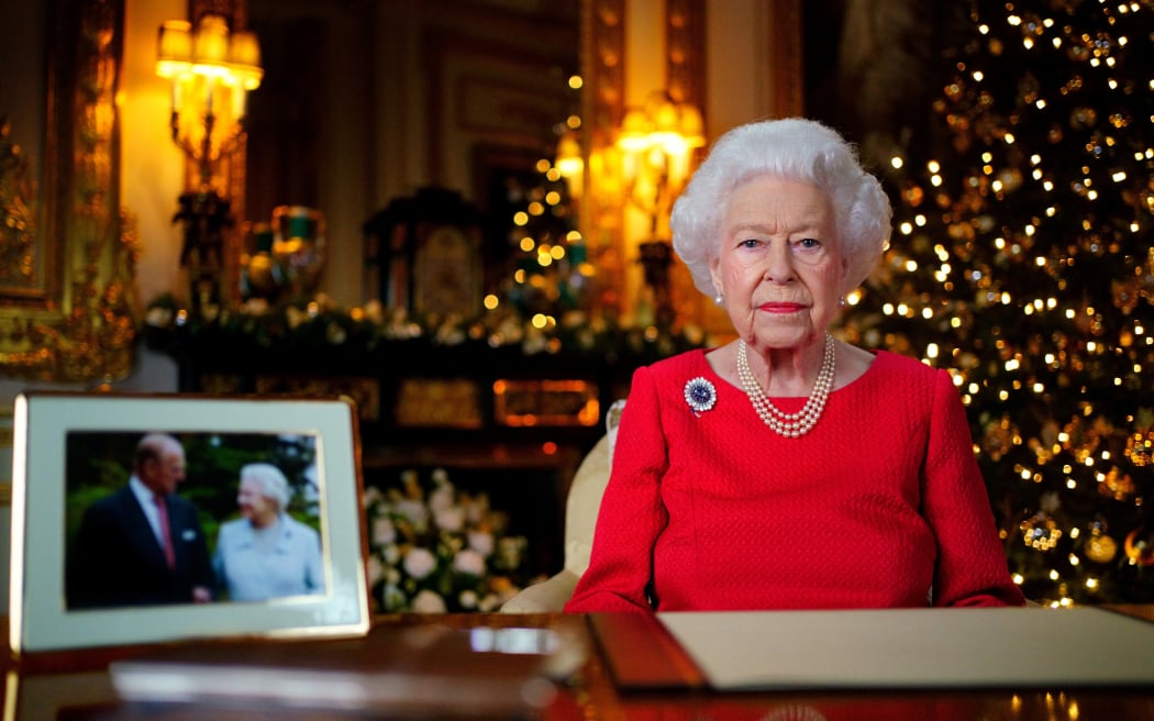 Queen Elizabeth II posing for a photograph as she recorded her last Christmas Day message, with a photograph of herself and her late husband Prince Philip, Duke of Edinburgh, at Windsor Castle, west of London.