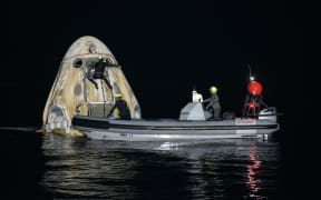 Support teams working around the SpaceX Crew Dragon Resilience spacecraft shortly after it landed