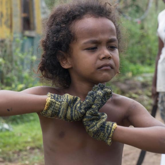 An un-named boy in Vanuatu puts in his father's gloves and begins to help the clean-up.