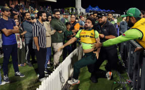 Pakistan's Khushdil Shah (C) is held back after reacting to comments from the crowd during the third one day international (ODI) cricket match between New Zealand and Pakistan at Bay Oval in Mount Maunganui on April 5, 2025. (Photo by Michael Bradley / AFP)