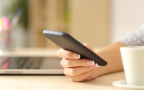 Close up of a woman hand using a smart phone on a desk at home