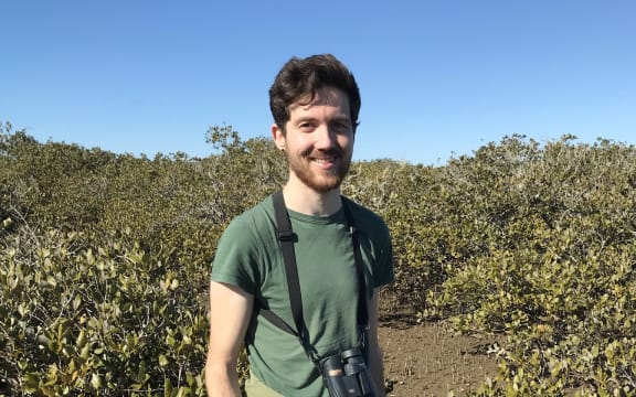 Jacques de Satge holds his banded rail footprint testing device & a small quadrat in front of some mangroves.