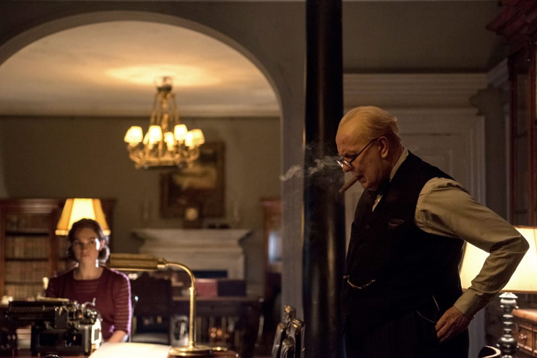 Lily James as Elizabeth Layton takes dictation from Gary Oldman as Winston Churchill in Darkest Hour.